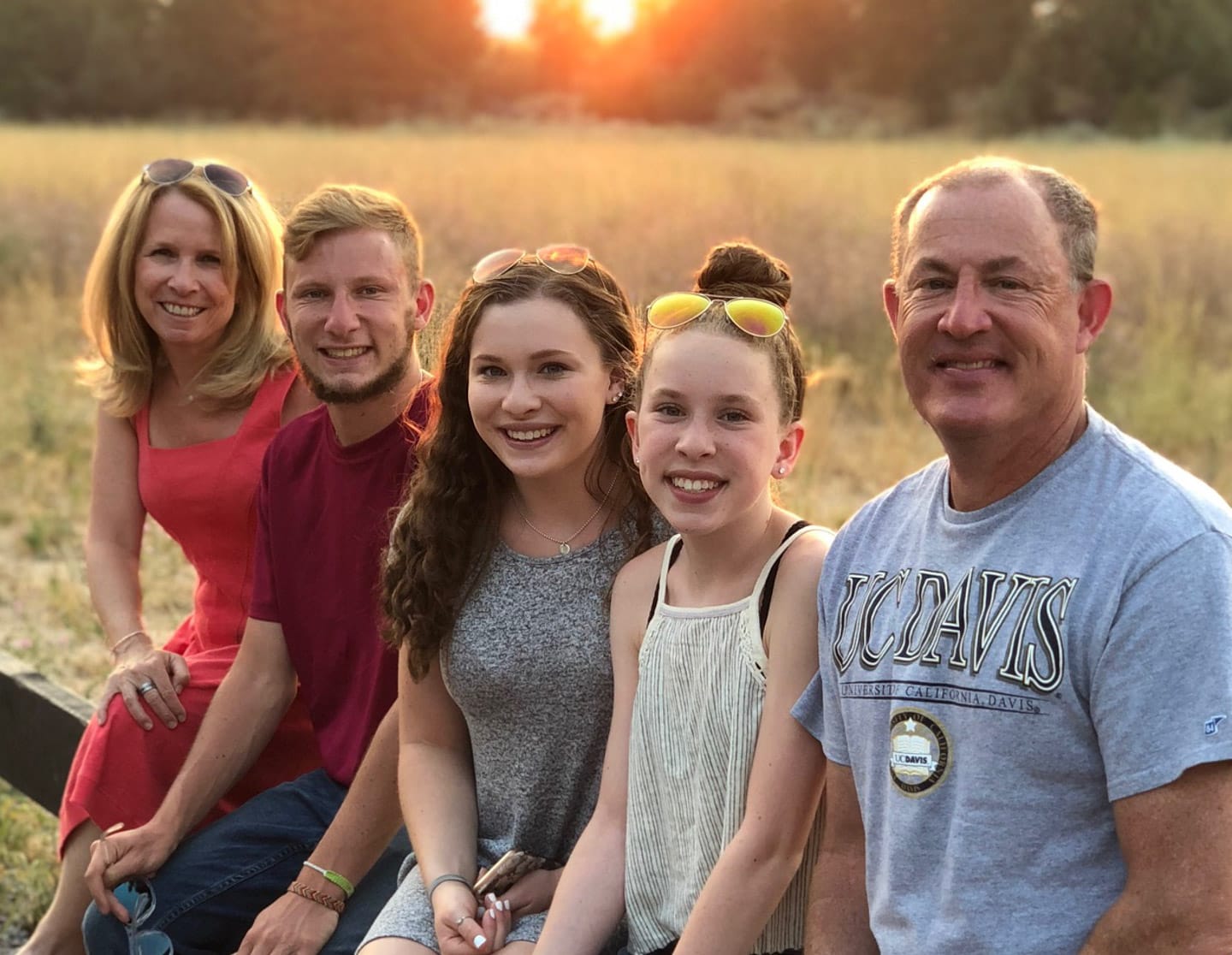 Family sitting on fence at sunset
